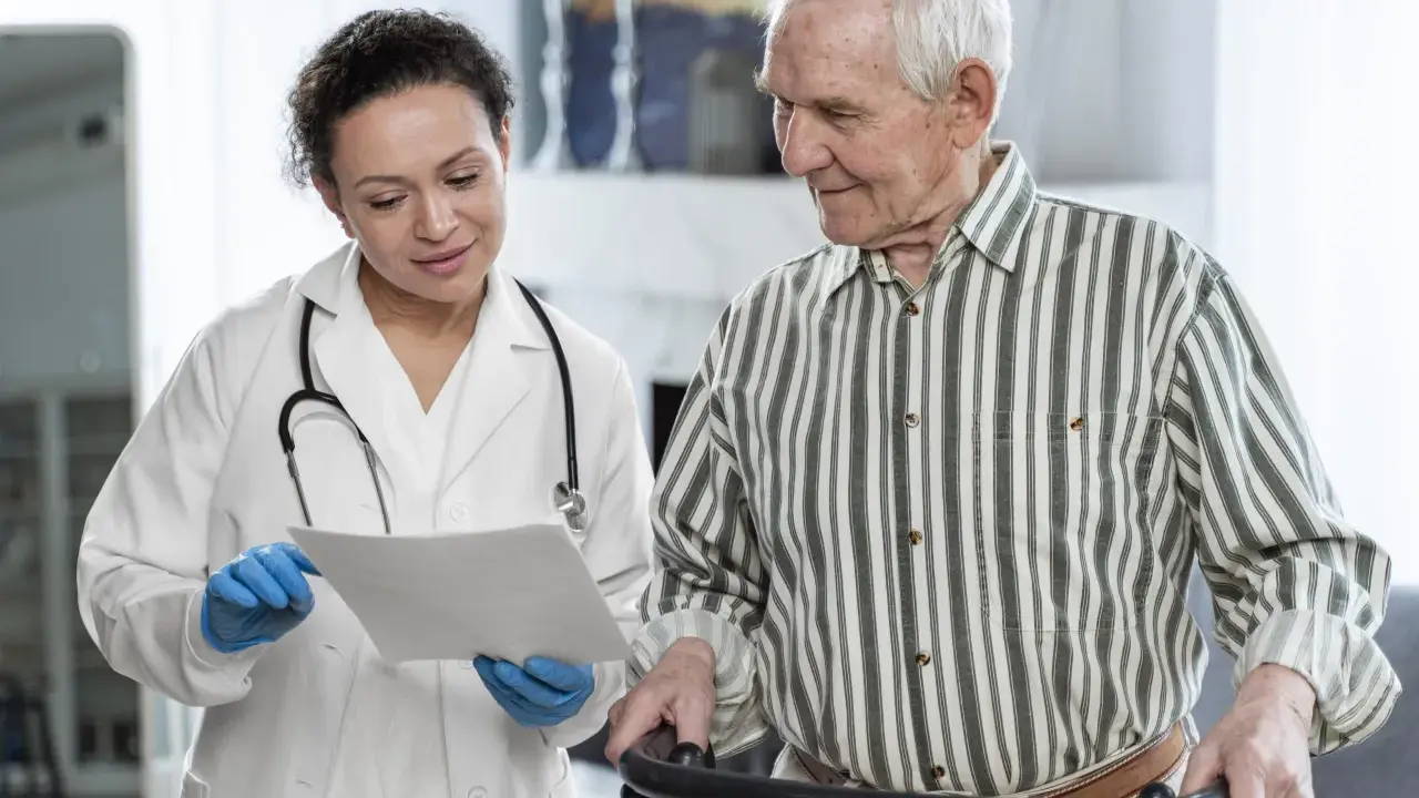 Medico spiega a paziente anziano con deambulatore il significato di un problema cognitivo, mostrando un documento.