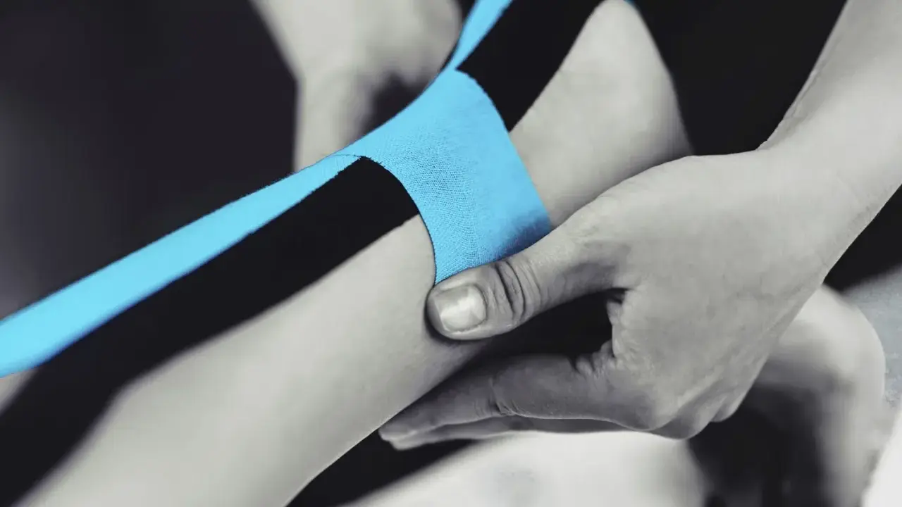 Applicazione di nastro kinesiologico blu e nero per supportare il tendine d'Achille.