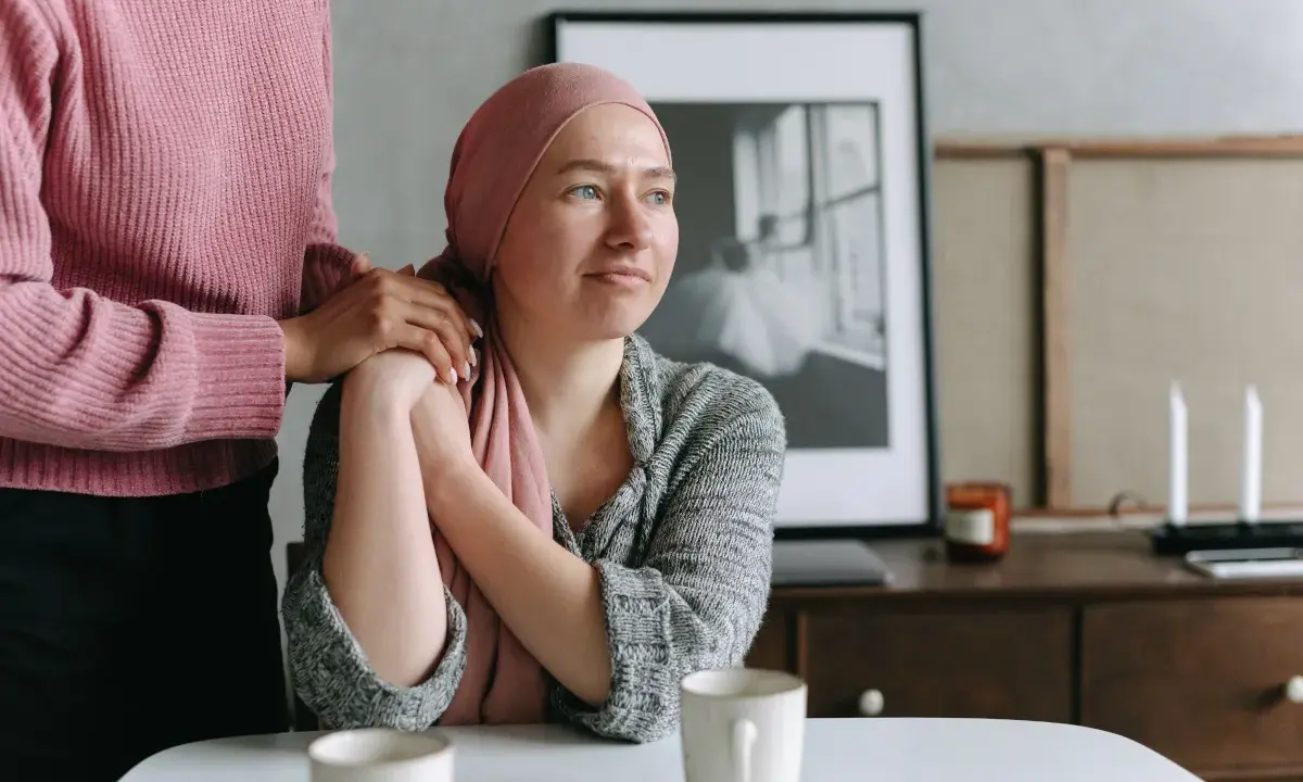 Una donna con un foulard rosa appoggiata a un'altra donna. Un esempio di cure palliative che offre conforto e supporto.