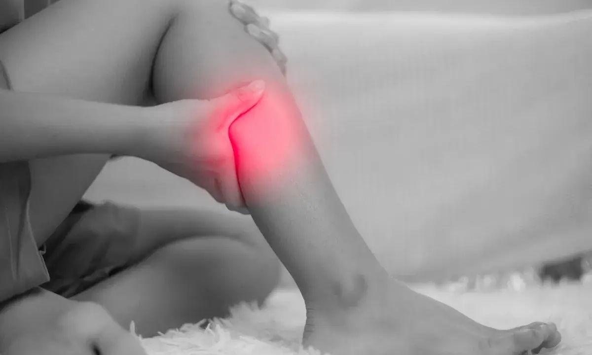 Donna che si tiene la gamba, evidenziata in rosso, a causa di dolori alle gambe, un possibile problema neurologico.