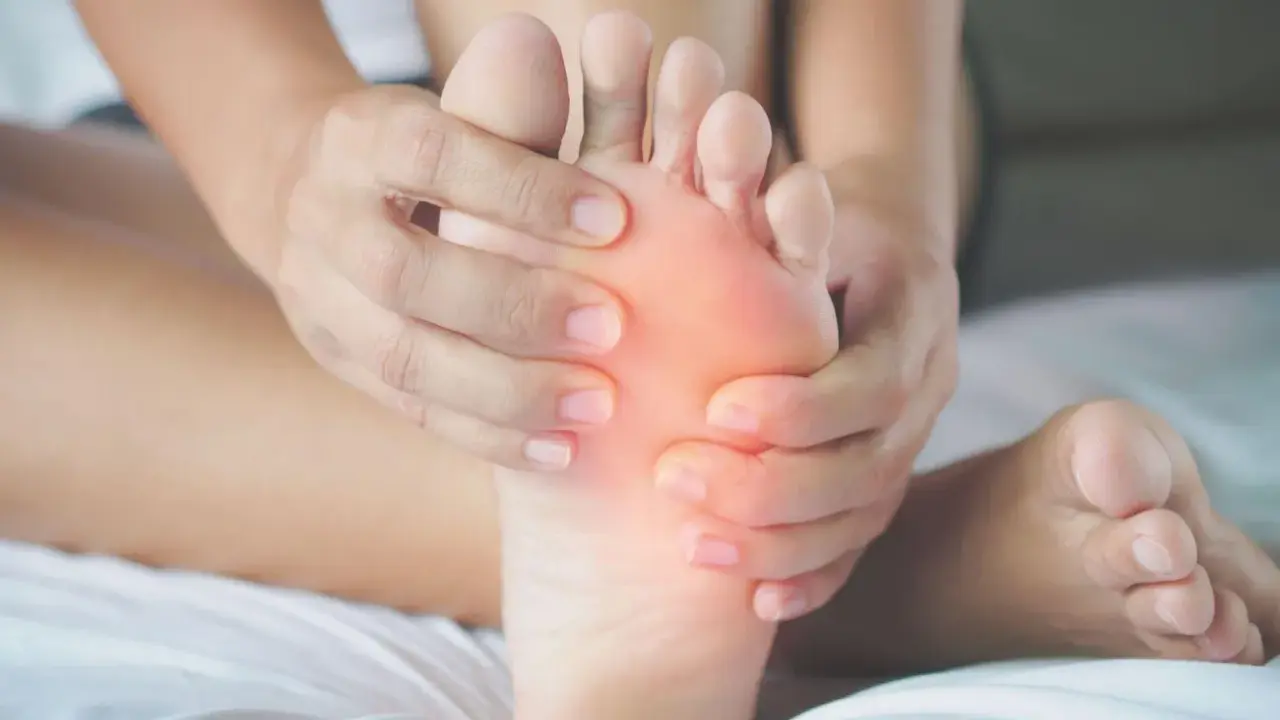 Mani che massaggiano la pianta del piede, evidenziando un'area arrossata. Potrebbe essere utile per chi soffre di metatarsalgia esercizi mirati.