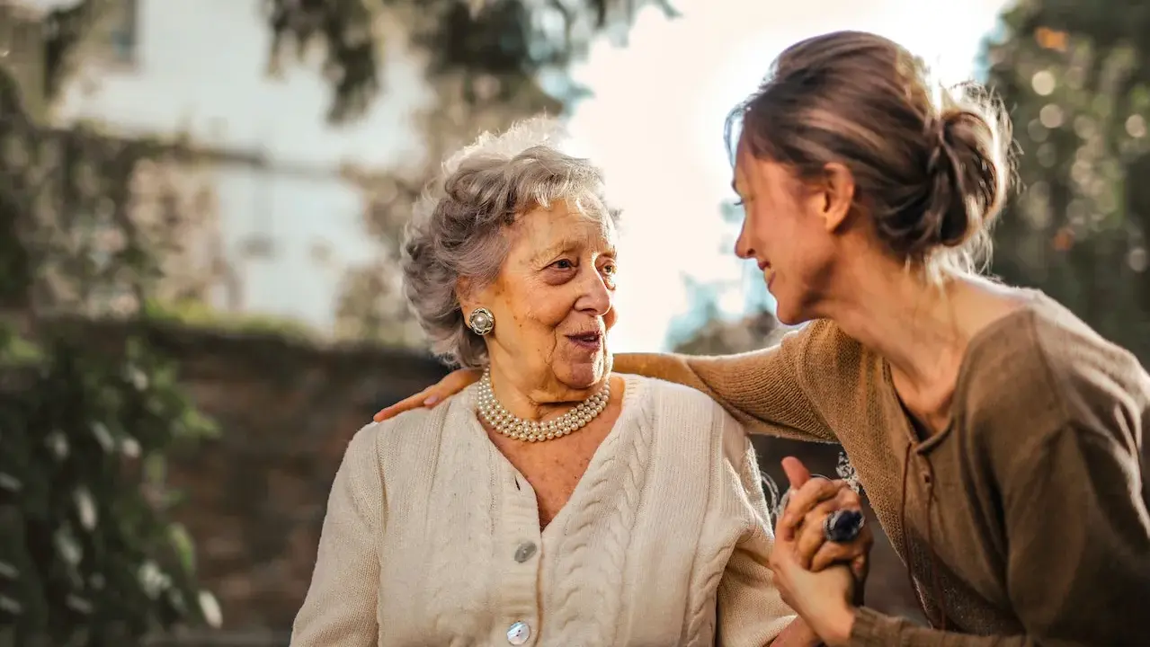 Una donna accarezza la spalla di un'anziana, un gesto di affetto che può alleviare i sintomi della demenza senile avanzata.