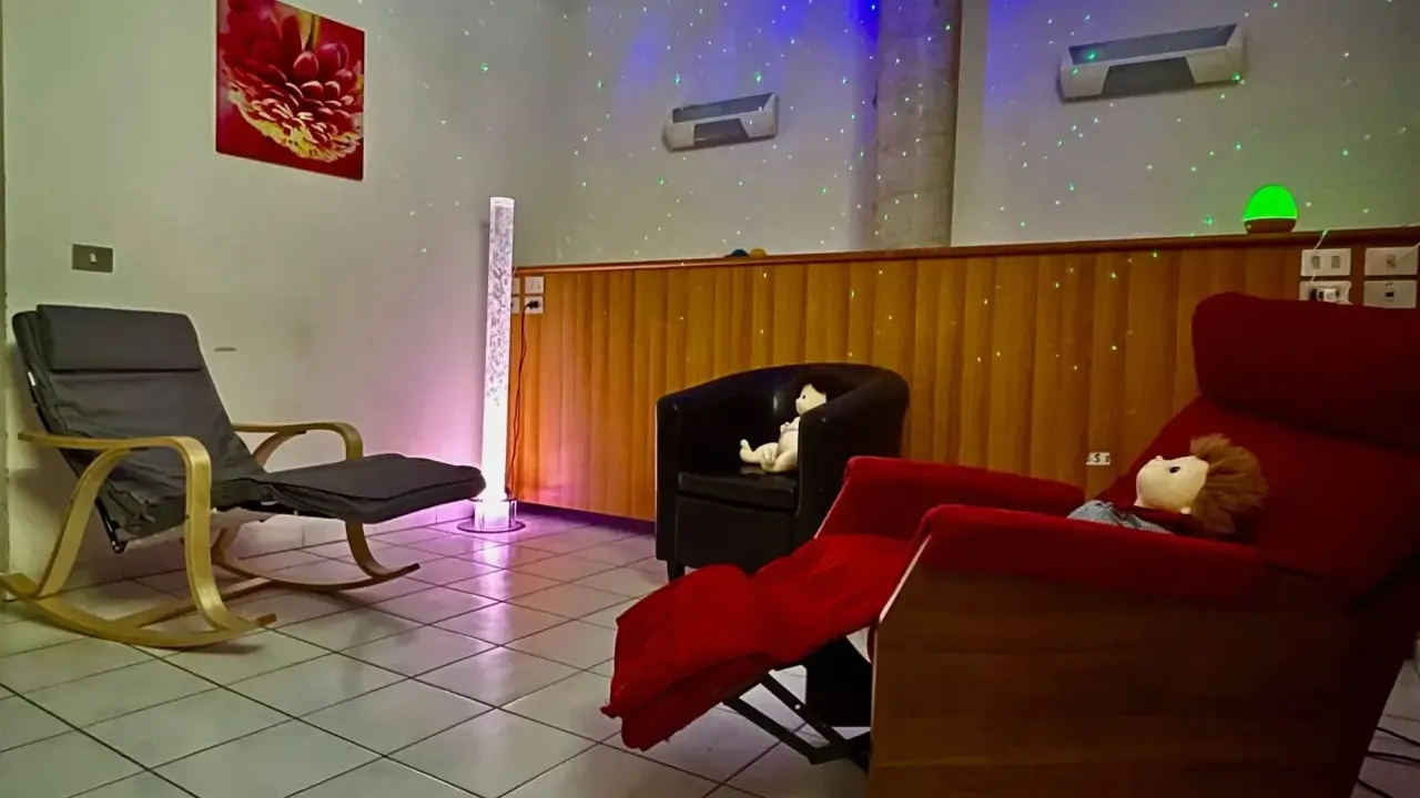 Una stanza snoezelen accogliente con sedie comode, luci soffuse e un'atmosfera rilassante.