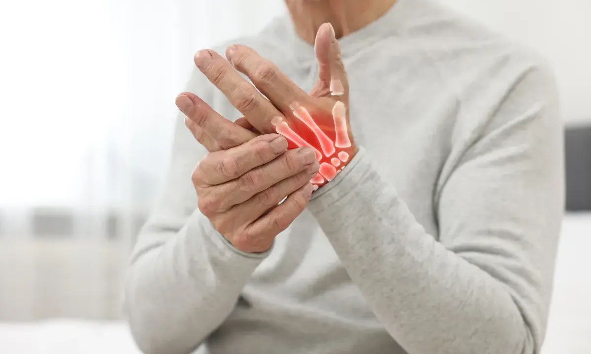 Uomo anziano con mani che mostrano i sintomi dell'osteoartrosi, con ossa evidenziate in rosso per indicare infiammazione.