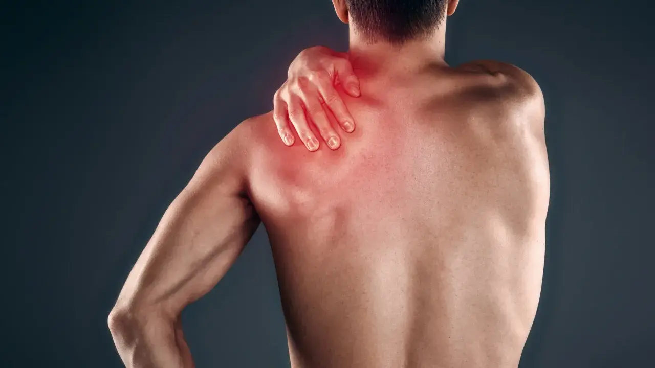 Uomo con mano sulla spalla, evidenziata in rosso, che indica dolore muscolare, forse mialgia da farmaci.