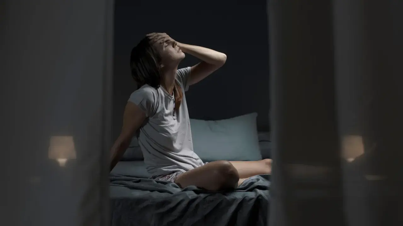Donna a letto, con la mano sulla fronte, soffre il caldo notturno. Forse il cortisone fa sudare di notte.