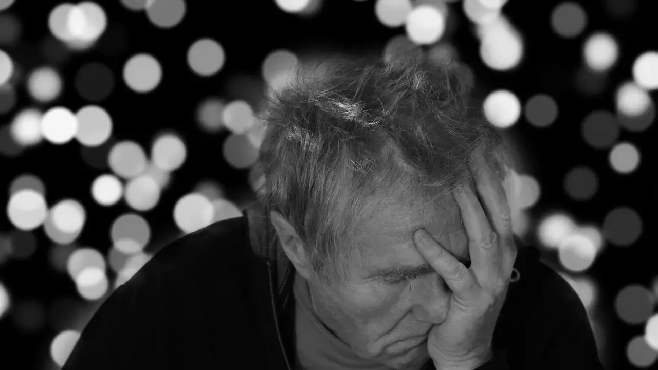 Uomo anziano con mano sulla fronte, pensieroso. L'Alzheimer può manifestarsi a diverse età, ma è più comune dopo i 65 anni.