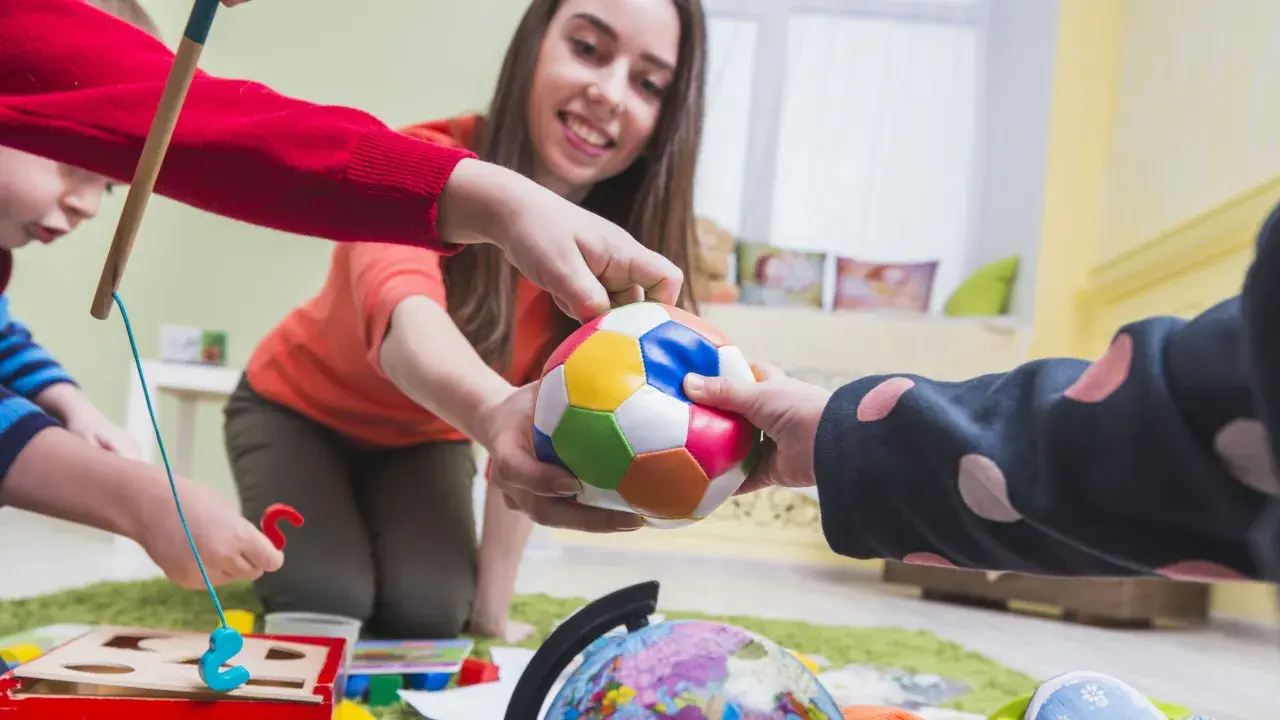 Bambini e terapista giocano con una palla colorata, un globo e un gioco di incastri. La terapia occupazionale cos'è? È questo: gioco e apprendimento.