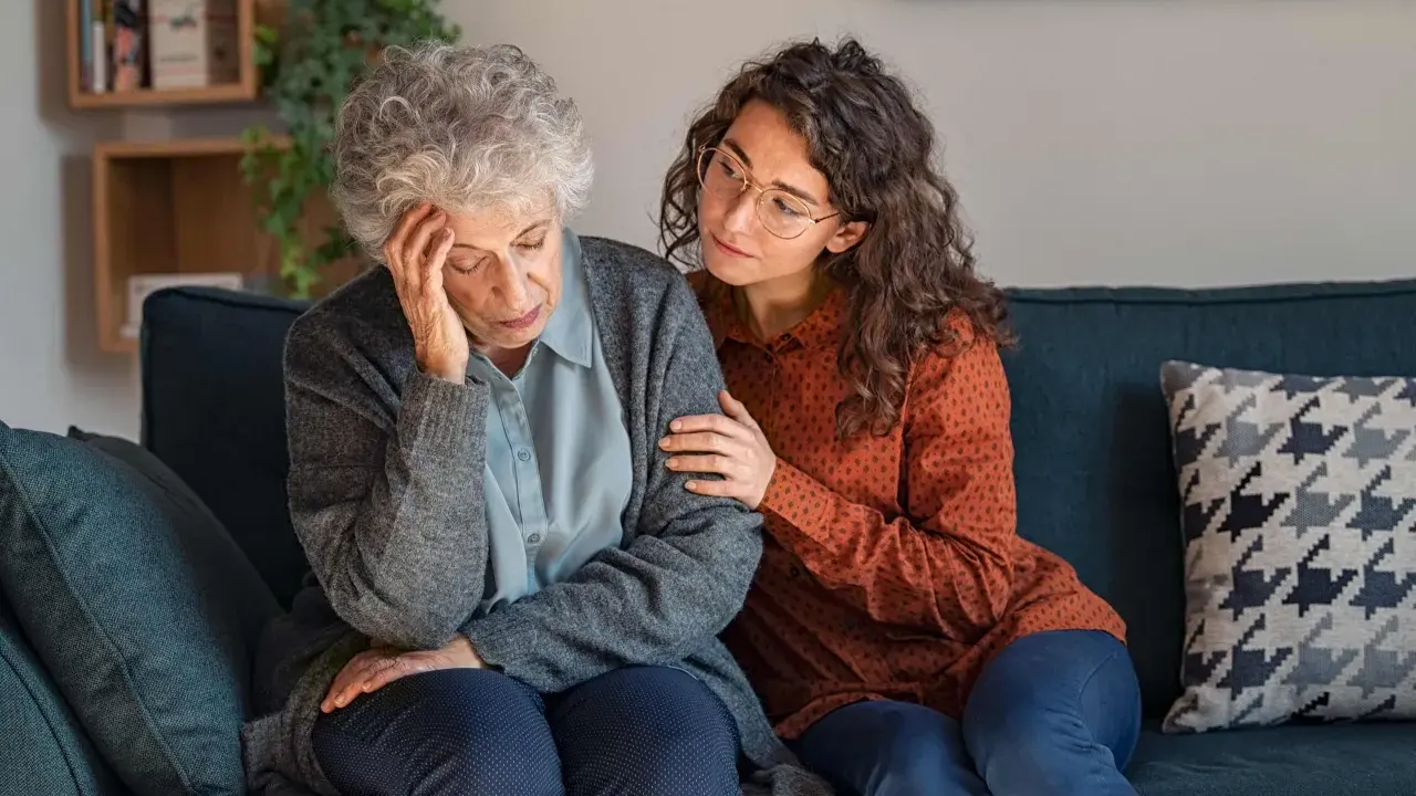 Una giovane donna conforta un'anziana con Alzheimer, mostrando quando ricoverare un malato di Alzheimer.
