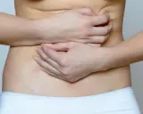Mani che stringono l'addome, indicando il disagio delle coliche addominali.