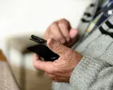 Mani anziane che tengono uno smartphone, forse per capire come fare lo SPID.