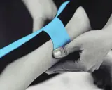 Applicazione di nastro kinesiologico blu e nero per supportare il tendine d'Achille.