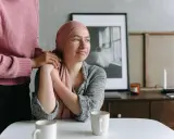 Una donna con un foulard rosa appoggiata a un'altra donna. Un esempio di cure palliative che offre conforto e supporto.