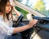 Donna in auto, con un fazzoletto sulla fronte, soffre di sudorazione eccessiva al minimo sforzo, cercando sollievo vicino alla bocchetta dell'aria.