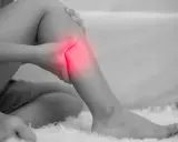 Donna che si tiene la gamba, evidenziata in rosso, a causa di dolori alle gambe, un possibile problema neurologico.