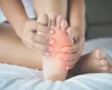 Mani che massaggiano la pianta del piede, evidenziando un'area arrossata. Potrebbe essere utile per chi soffre di metatarsalgia esercizi mirati.