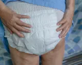 Mani anziane che sistemano un doppio pannolone per garantire il massimo comfort e protezione.