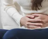 Mani che stringono l'addome, forse per dolori o crampi. Le feci verdi potrebbero essere un sintomo.