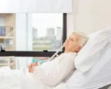 Anziana allettata in ospedale, con mani giunte. La domanda "quanto può vivere un anziano allettato" è complessa e dipende da molti fattori.