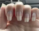 Dita con unghie curate, leggermente incurvate, che mostrano una french manicure naturale.
