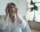 Donna anziana con mani sulle tempie, espressione preoccupata, forse un momento di **perdita di memoria improvvisa**.