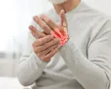 Uomo anziano con mani che mostrano i sintomi dell'osteoartrosi, con ossa evidenziate in rosso per indicare infiammazione.