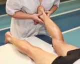 Mani esperte eseguono un massaggio trasverso profondo alla caviglia e al polpaccio di un atleta, alleviando la tensione muscolare.