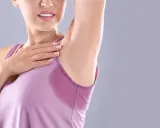 Donna con ascella bagnata, un segno di sudorazione eccessiva. Le cause possono essere molteplici, dallo stress al caldo.