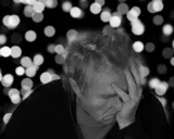 Uomo anziano con mano sulla fronte, pensieroso. L'Alzheimer può manifestarsi a diverse età, ma è più comune dopo i 65 anni.