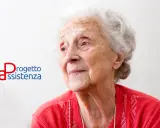 Ritratto di un'anziana signora con capelli bianchi, che guarda lontano. Accanto, il logo "Progetto Assistenza", che evoca cura e supporto, anche in caso di demenza senile a 88 anni.