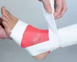 Applicazione di bendaggio ossido di zinco sulla caviglia per supporto e protezione.