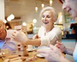 Anziani sorridono giocando a Jenga, un'attività stimolante per anziani con demenza.