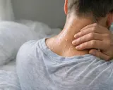 Uomo con sudorazione notturna visibile sul collo, mentre si tocca la nuca.