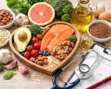 Salmone, avocado, noci e altri cibi sani per combattere il colesterolo 260 dopo 50 anni. Stetoscopio e ricetta medica in primo piano.
