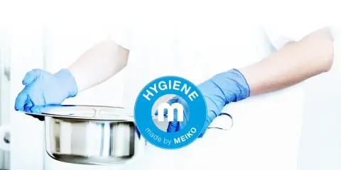 Mani guantate presentano una padella metallica, pronta per essere usata. Il logo MEIKO sottolinea l'igiene.