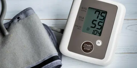 Misuratore di pressione con bracciale e display che mostra 75/55, valori che potrebbero indicare pressione bassa anziani 90 anni.
