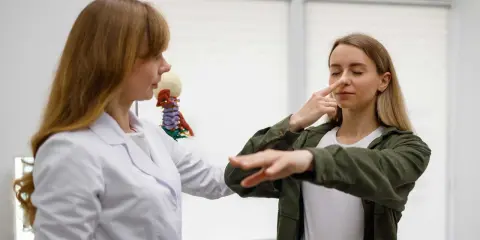 Medico osserva paziente eseguire il test di Romberg, toccandosi il naso con gli occhi chiusi.