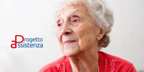 Ritratto di un'anziana signora con capelli bianchi, che guarda lontano. Accanto, il logo "Progetto Assistenza", che evoca cura e supporto, anche in caso di demenza senile a 88 anni.