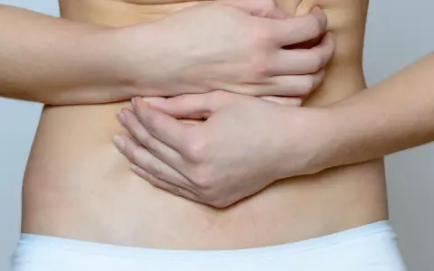Mani che stringono l'addome, indicando il disagio delle coliche addominali.