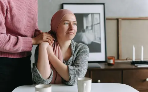 Una donna con un foulard rosa appoggiata a un'altra donna. Un esempio di cure palliative che offre conforto e supporto.