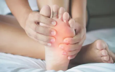 Mani che massaggiano la pianta del piede, evidenziando un'area arrossata. Potrebbe essere utile per chi soffre di metatarsalgia esercizi mirati.