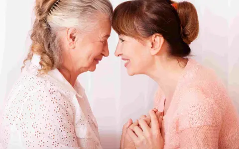 Un abbraccio tra madre e figlia, un momento di affetto che può aiutare a gestire i sintomas de alzheimer, con mani che si stringono.