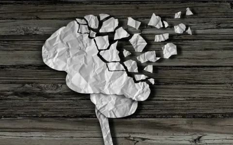 Cervello di carta sgretolato, simbolo dei vuoti di memoria negli anziani. Frammenti che si staccano, come ricordi perduti.