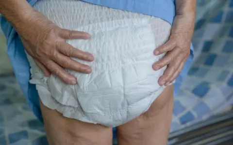Mani anziane che sistemano un doppio pannolone per garantire il massimo comfort e protezione.