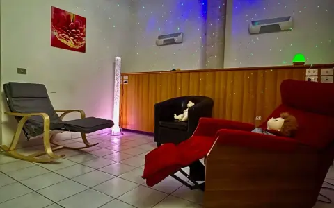 Una stanza snoezelen accogliente con sedie comode, luci soffuse e un'atmosfera rilassante.