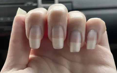 Dita con unghie curate, leggermente incurvate, che mostrano una french manicure naturale.