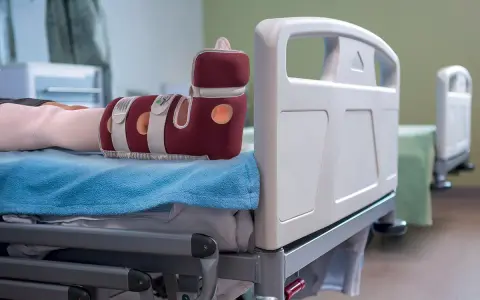 Piede con tutore per prevenire la piaga da decubito sul tallone, appoggiato su un letto ospedaliero.