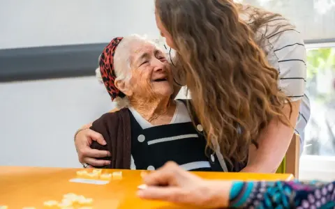 Giovane abbraccia anziana sorridente, un momento di affetto che contrasta il timore del decadimento cognitivo improvviso.