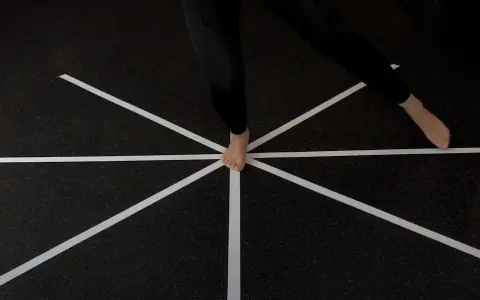 Persona esegue un test di equilibrio su un pavimento con nastro bianco a raggiera.