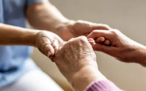 Mani che si stringono, un gesto di cura e supporto. Un'immagine che evoca il valore del bonus caregiver e l'importanza di chi assiste gli altri.